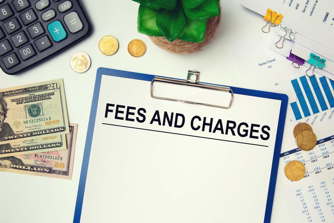 Paper with Fees and Charges on the table, calculator and money